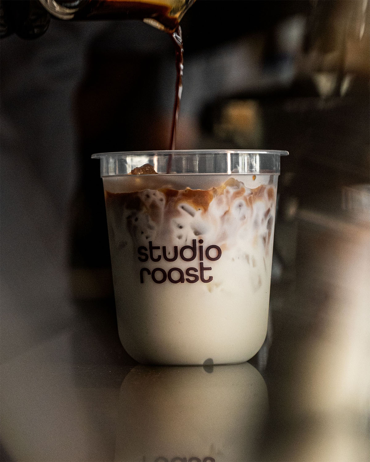 Studio Roast Cold Coffee being Poured into Studio Roast labeled Cup